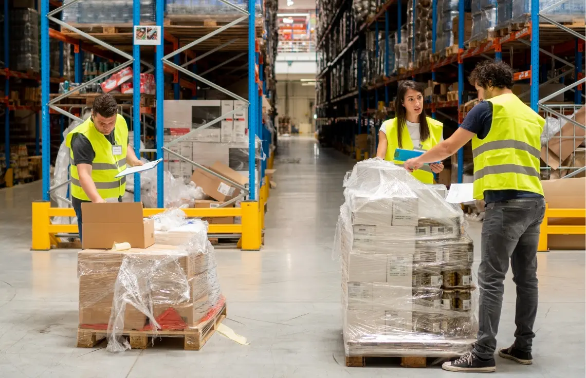 Two warehouse workers checking a wrapped pallet of cartons