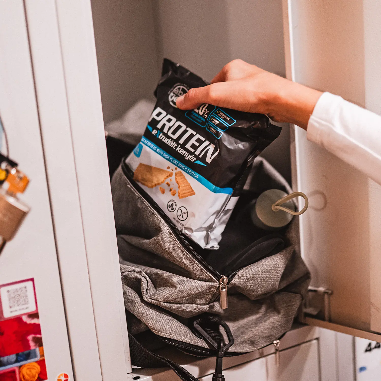 A hand putting a pack of Abonett Protein crackerbread into a gym bag